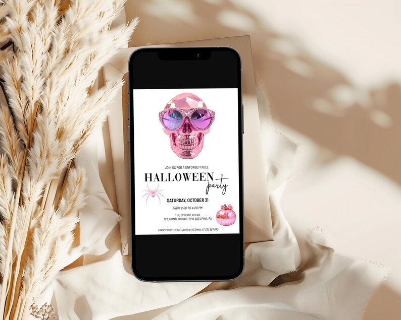 May include: A pink and white Halloween party invitation with a pink skull wearing sunglasses. The text on the invitation reads "Join us for an unforgettable Halloween party. Saturday, October 31. 7:00 PM - 1:00 AM. The Spook House. 123 Monte Road, Philadelphia, PA. RSVP by October 27 to confirm.