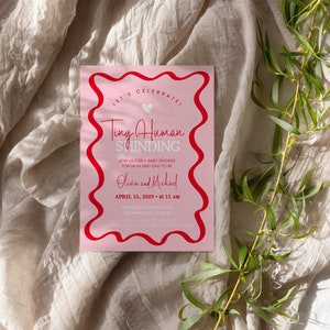 May include: Pink baby shower invitation with a red wavy border. The invitation says "Let's Celebrate! Tiny Human Shinding" and includes the date and time of the event.