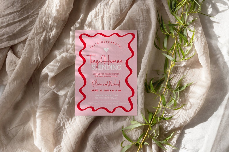 May include: Pink baby shower invitation with a red wavy border. The invitation says "Let's Celebrate! Tiny Human Shinding" and includes the date and time of the event.