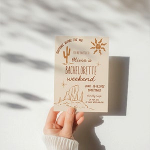 May include: A tan card with a brown illustration of a cactus, a sun, and a desert landscape. The text on the card reads "Scottsdale Before the Veil, You are invited to Olivia's Bachelorette Weekend, June 15-18, 202X, Scottsdale, kindly RSVP by May 10th to (phone number)"