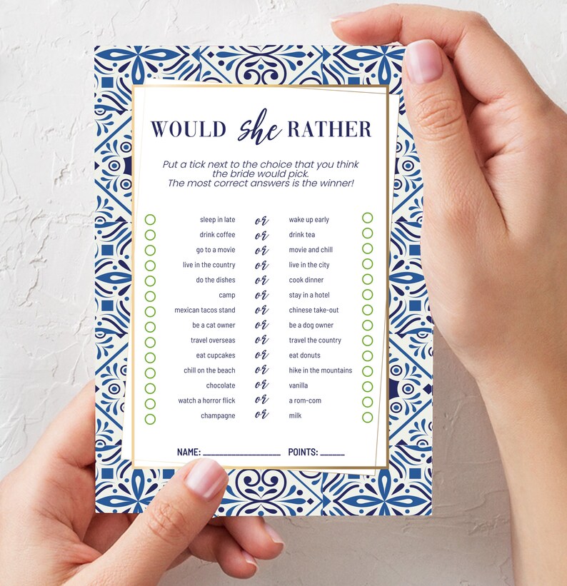 May include: A bridal shower game card with a blue and white patterned border. The card reads "Would She Rather" and includes a list of choices for the bride to select. The card is held by a person.