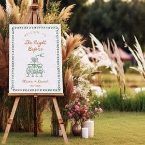 May include: A white sign with green and orange text on an easel. The sign says "Welcome to The Night Before Olivia + David 05.21.2035". The sign is decorated with a drawing of a champagne tower.