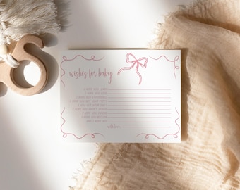 May include: A white card with pink script that reads "wishes for baby" and includes a pink bow. The card has lines for writing wishes for a new baby.