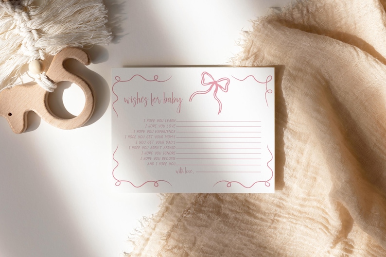 K&ouml;nnte beinhalten: Eine wei&szlig;e Karte mit rosa Schrift, auf der "wishes for baby" steht und ein rosa Schleife enthalten ist. Die Karte hat Linien zum Schreiben von W&uuml;nschen f&uuml;r ein Neugeborenes.