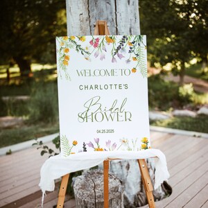 May include: White sign with green floral border and text that reads "Welcome to Charlotte's Bridal Shower 04.25.2025".