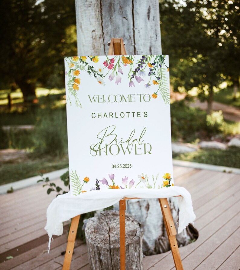 May include: White sign with green floral border and text that reads "Welcome to Charlotte's Bridal Shower 04.25.2025".