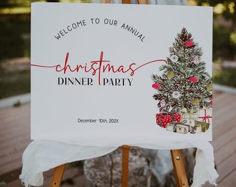 May include: White sign with black text that reads "Welcome to our annual Christmas Dinner Party" in cursive script. The text "Christmas" is in red. The sign also includes a watercolor illustration of a Christmas tree with presents underneath. The date "December 10th 202X" is printed below the text.