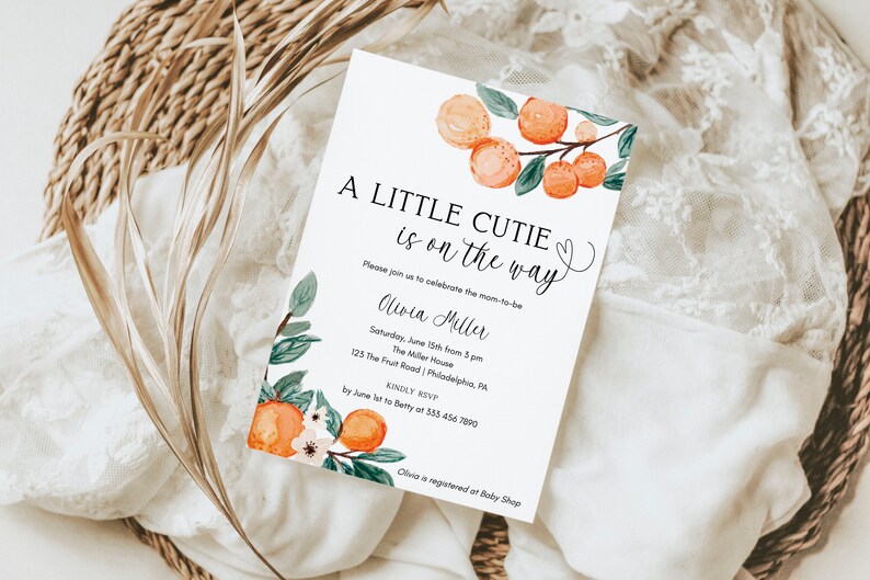 May include: A white baby shower invitation with orange blossoms and green leaves. The text reads "A Little Cutie is on the way". The invitation includes the name "Oliwia Miller", the date and time of the shower, the address, and RSVP information.