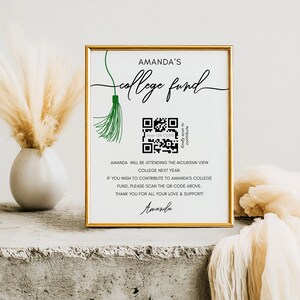 Op de afbeelding: Een wit bord met een gouden lijst en een groene kwast. Het bord heeft de tekst "Amanda's College Fund" en bevat een QR-code. De tekst onder de QR-code luidt: "Amanda gaat volgend jaar naar het Mountain View College. Als je wilt bijdragen aan Amanda's collegefonds, scan dan de QR-code hierboven. Bedankt voor al je liefde en steun! Amanda."