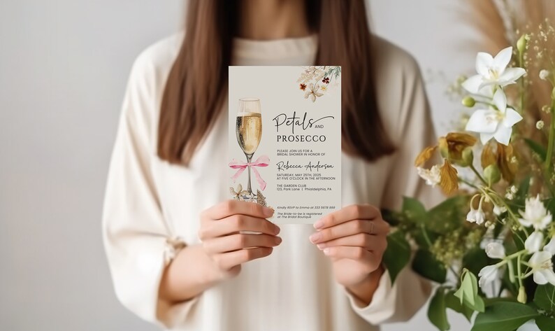 May include: A white invitation card with a watercolor illustration of a champagne flute and floral details. The text reads "Petals and Prosecco" and includes details for a bridal shower in honor of Rebecca Anderson. The event is scheduled for Saturday, May 25th, 2023 at 2:00 PM at The Garden Club, 123 Park Lane, Philadelphia, PA.