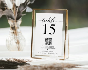 May include: A gold-framed table number card with the number 15 printed in black. The card also includes a QR code and the text "Please share your photos with us! Simply scan the QR code with your phone camera & upload to our website. Emma + Jason April 21, 2023 | Philadelphia, PA"