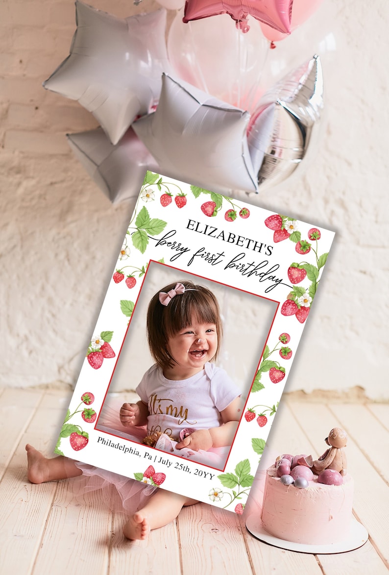 Puede incluir: Un accesorio de cabina de fotos blanco con un borde rojo y un tema de fresa. El accesorio dice "Elizabeth's berry first birthday" y tiene un recorte de foto en el medio. El accesorio tambi&eacute;n incluye el texto "Philadelphia, Pa | July 25th, 20YY".