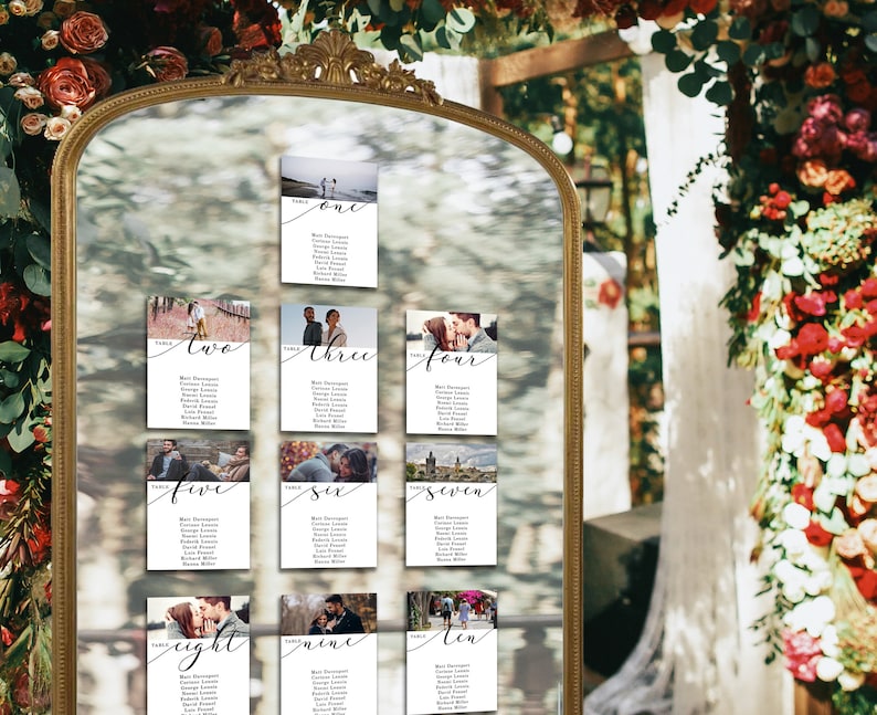 May include: A mirror with a gold frame reflecting a wedding seating chart. The chart is made up of ten cards with photos and guest names. Each card has a table number and the word "Table" written in cursive.