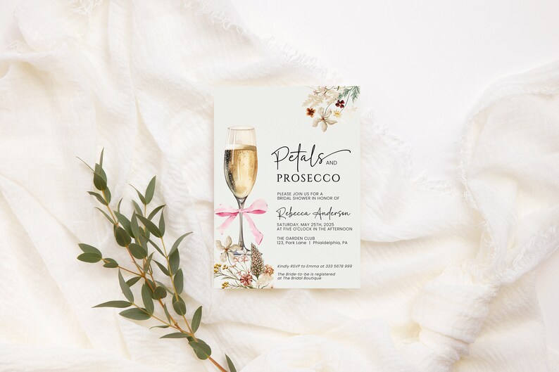 May include: A white card with a floral design and a glass of champagne. The text on the card reads "Petals and Prosecco" and includes details for a bridal shower for Rebecca Anderson.