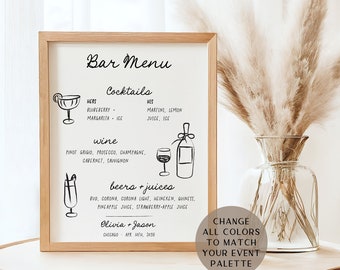 May include: A framed bar menu with a wooden frame, featuring handwritten text and illustrations of cocktails, wine, and beer. The menu includes the names of the couple and the date of the event. A vase of pampas grass sits nearby.