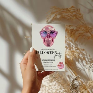 May include: A pink skull wearing sunglasses and a pink pumpkin on a white invitation card that says "Join us for a unforgettable Halloween party. Saturday, October 29. From 7:00 PM to 1:00 AM. The Spooky House. 1234 Invited Road, Philadelphia, PA. RSVP by October 27 at 555-555-5555."