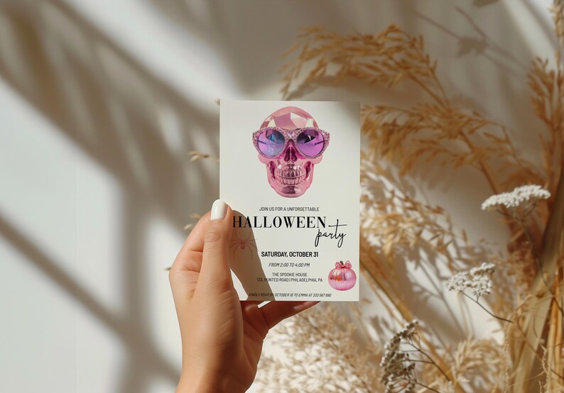 May include: A pink skull wearing sunglasses and a pink pumpkin on a white invitation card that says "Join us for a unforgettable Halloween party. Saturday, October 29. From 7:00 PM to 1:00 AM. The Spooky House. 1234 Invited Road, Philadelphia, PA. RSVP by October 27 at 555-555-5555."