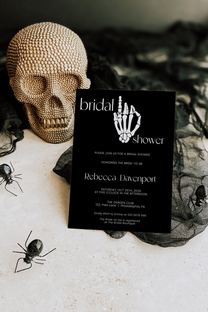 K&ouml;nnte beinhalten: Eine schwarz-wei&szlig;e Einladung zur Bridal Shower mit einer Skeletthand, die einen Ring h&auml;lt. Die Einladung lautet "bridal shower" und enth&auml;lt den Namen der Braut, das Datum, die Uhrzeit und den Ort der Veranstaltung. Au&szlig;erdem enth&auml;lt sie die RSVP-Informationen.