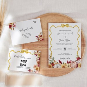 May include: Fall wedding invitation suite with a floral design featuring pumpkins, leaves, and flowers in shades of red, yellow, and white. The invitation includes the names Amanda Buccnport and Jason Miller, the date October 21, 2023, and the location The Garden Hotel.