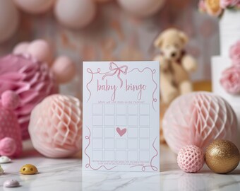 Könnte beinhalten: Eine rosa und weiße Baby-Bingo-Karte mit einer rosa Schleife und dem Text "baby bingo" und "Was erhält die werdende Mutter?" Die Karte hat ein 5x5-Raster mit leeren Feldern und einem rosa Herzen im mittleren Feld.