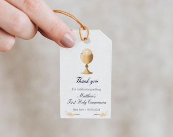 May include: White thank you tag with gold and blue text. The tag features a gold chalice with a host and a cross. The text reads "Thank you for celebrating with us Matthew's First Holy Communion New York - 04/15/2029".