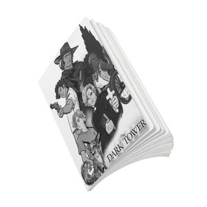 May include: A black and white notebook featuring a cover illustration of several characters and a small creature, with the text The Dark Tower printed in the lower right corner. The notebook is shown at an angle with its pages partially fanned out.
