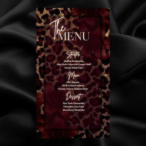 May include: A rectangular menu card featuring a dark red and black leopard print background with gold glitter accents and deep red floral motifs. The text reads The Menu, Starter, Stuffed Mushrooms, Mini Crab Cakes, Caesar Salad Cups, Main, Filet Mignon, Herb-Crusted Salmon, Creamy Tuscan Chicken Pasta, Dessert, New York Cheesecake, Chocolate Lava Cake, Strawberry Shortcake.