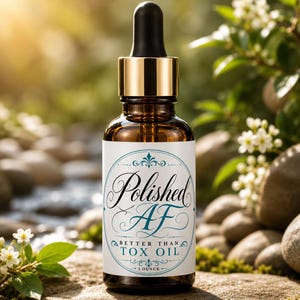 May include: An amber glass dropper bottle with a gold collar and black dropper top. The white label features a teal oval border and black text that reads Polished AF BETTER THAN TOX OIL 1 OUNCE in a decorative script and sans-serif font style.