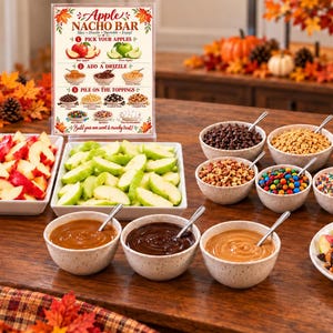 May include: An Apple Nacho Bar sign with instructions, two rectangular white platters filled with red and green apple slices, three bowls of sauces, and six bowls of various toppings including chocolate chips, nuts, and marshmallows.