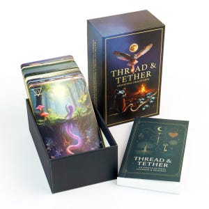 May include: A deck of oracle cards titled Thread & Tether in a black box, featuring an owl and moon illustration on the lid. The set includes a stack of cards with a forest and worm graphic, and a companion guidebook with gold line art on a dark cover.
