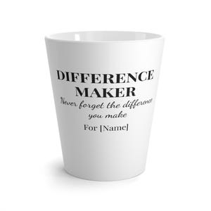 Può includere: Una tazza conica bianca con testo stampato in nero che recita DIFFERENCE MAKER, seguito dal testo in corsivo Never forget the difference you make, e l'ultima riga For [Name] in un semplice carattere serif nero sulla parte anteriore.