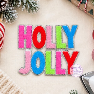 May include: A set of colorful chenille letter patches spelling out the words HOLLY JOLLY. Each letter features a vibrant, fuzzy texture in shades of hot pink, red, light pink, lime green, and blue, all outlined with a shimmering silver border.