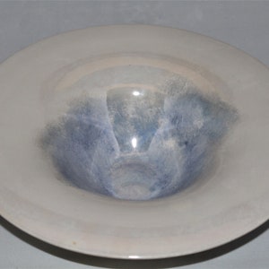 May include: A white ceramic bowl with a blue and gray glaze. The bowl has a wide rim and a shallow depth.