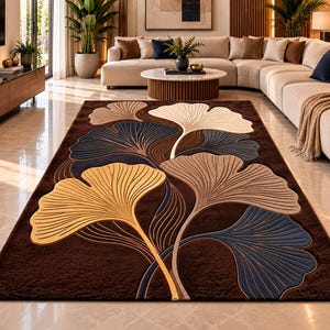 May include: A rectangular area rug featuring a deep brown background with a large-scale ginkgo leaf pattern. The leaves are rendered in shades of cream, golden yellow, and dark blue, with raised, textured lines defining the leaf veins.