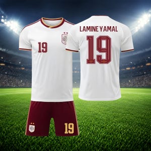 May include: A white soccer jersey with maroon trim, the number 19, and a team crest on the front, paired with maroon shorts featuring the number 19 and a crest. The back of the jersey displays the name LAMINE YAMAL and the number 19 in maroon.