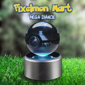 Puede incluir: Una esfera de cristal transparente con una figura de Mega Diancie grabada con láser en su interior, que se asemeja a una Poké Ball con una banda negra. La esfera descansa sobre una base cilíndrica plateada. El texto dice Pixelmon Mart y MEGA DIANCIE.