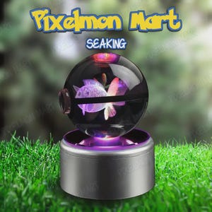 Puede incluir: Una esfera de cristal transparente con una figura de Seaking grabada con láser en su interior, sobre una base cilíndrica plateada con iluminación púrpura. El texto Pixelmon Mart y SEAKING aparece arriba en azul y amarillo.