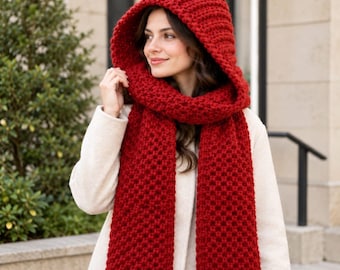 May include: A vibrant red hooded scarf featuring a chunky, textured knit pattern. The accessory consists of a deep, integrated hood that transitions into two long, wide panels that drape down the front, crafted from thick yarn.