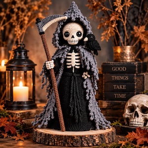 May include: A crocheted grim reaper doll featuring a white skull head with large black eyes, a black robe, and a tattered grey hooded cloak. The figure holds a brown scythe with a silver blade and has a small black bird perched on its shoulder.