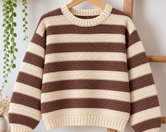 May include: A long-sleeve crochet sweater featuring horizontal stripes in alternating dark brown and cream colors. The garment has a round neckline, ribbed cuffs, and a ribbed hem, all constructed with a consistent textured stitch pattern.