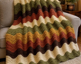 May include: A crochet blanket featuring a wavy chevron pattern in alternating horizontal stripes of cream, olive green, rust orange, mustard yellow, and dark brown. The textile has a thick, textured yarn construction with a soft, plush appearance.