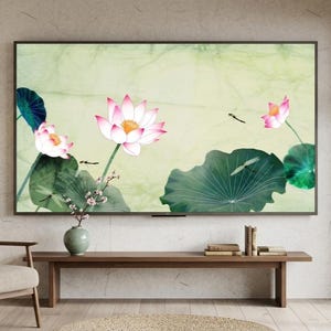 May include: A large rectangular television screen displaying a digital painting of pink lotus flowers and large green lily pads against a pale yellow background, with small dragonflies flying near the flowers, mounted on a textured wall.