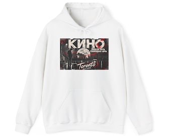 May include: A white hooded sweatshirt featuring a rectangular graphic print on the chest. The graphic depicts a silhouette of a person, a full moon, a city skyline, and the text KINO, Toronto, 05.11.2026, and Cyrillic characters.