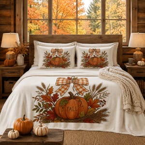 May include: A cream-coloured bedding set featuring a large central pumpkin graphic with the word FALL printed on it, surrounded by autumn leaves, wheat stalks, and a plaid bow. The set includes two matching rectangular pillows and a throw blanket.