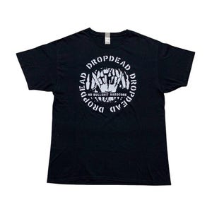 May include: A black short-sleeve t-shirt featuring a white circular graphic on the chest. The design includes the text DROPDEAD repeated around the circle, with a central illustration of hands and the text NO BULLSHIT HARDCORE printed below.