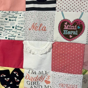 Op de afbeelding: Een patchwork deken gemaakt van verschillende stoffen vierkanten in roze, witte en gele kleuren. De deken bevat teksten zoals "Lieblingsmensch", "Nela", "Mini Herzl", "I'M MY Daddy's GIRL AND MY Mommy's" en "17.07.2023 20:56 Uhr."