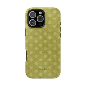 Puede incluir: Una funda para smartphone con un fondo verde oliva apagado y un patrón repetitivo de puntos circulares más claros de bordes suaves. La palabra kimokin está impresa en letras minúsculas oscuras cerca de la parte inferior central de la funda.