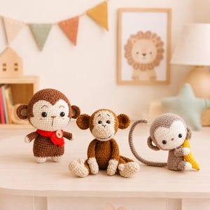 May include: Three crocheted monkey toys in different sizes and shades of brown. The left monkey wears a red scarf with a button. The middle monkey sits with light-colored hands and feet. The right monkey holds a small yellow crocheted banana.