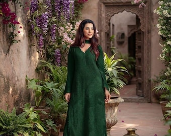 May include: A floor-length dark green long-sleeved tunic dress with a textured fabric surface, a V-neckline with a scalloped edge, and a matching choker collar, paired with wide-leg trousers in the same deep green shade and fabric.