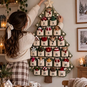May include: A wall-hanging crochet Christmas tree advent calendar in dark green with a cream-coloured star topper. It features twenty-four individual cream-coloured pockets, each numbered from 1 to 24, containing small crocheted holiday ornaments.